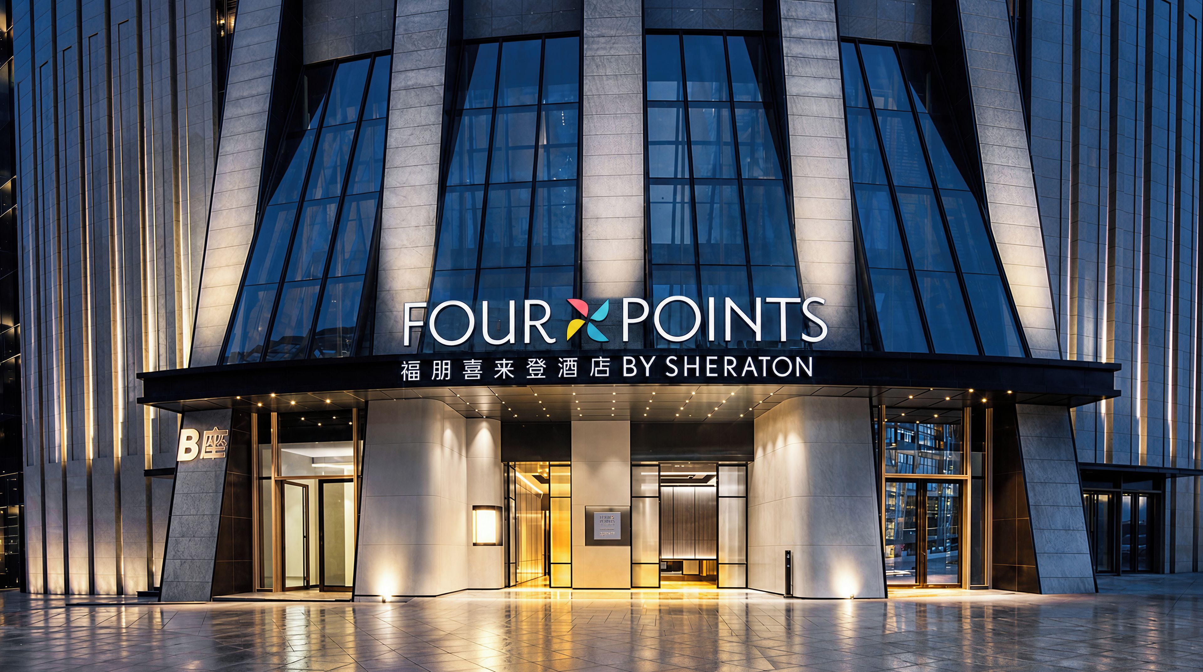 Fachada moderna de hotel com sinalização iluminada que diz 'FOUR POINTS' e 'BY SHERATON'.