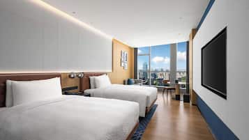 A hotel room with two beds, a large TV, and a city view.