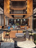 A bar area with seating, shelves with bottles, and a decorative ceiling.