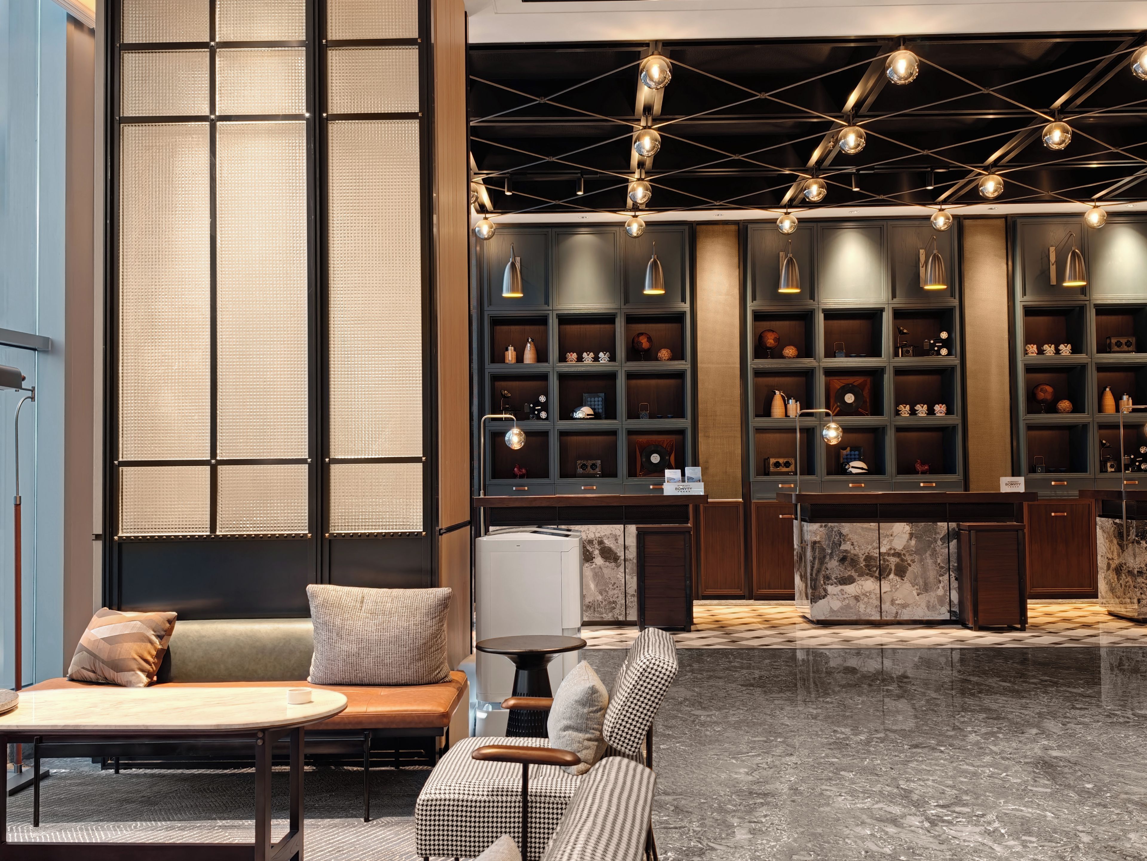 A modern lobby with a seating area, a reception desk, and a display of decorative items.