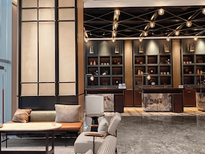 A modern lobby with a seating area, a reception desk, and a display of decorative items.