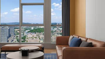 A modern living room with a leather sofa, a round coffee table, and a view of a cityscape through large windows.