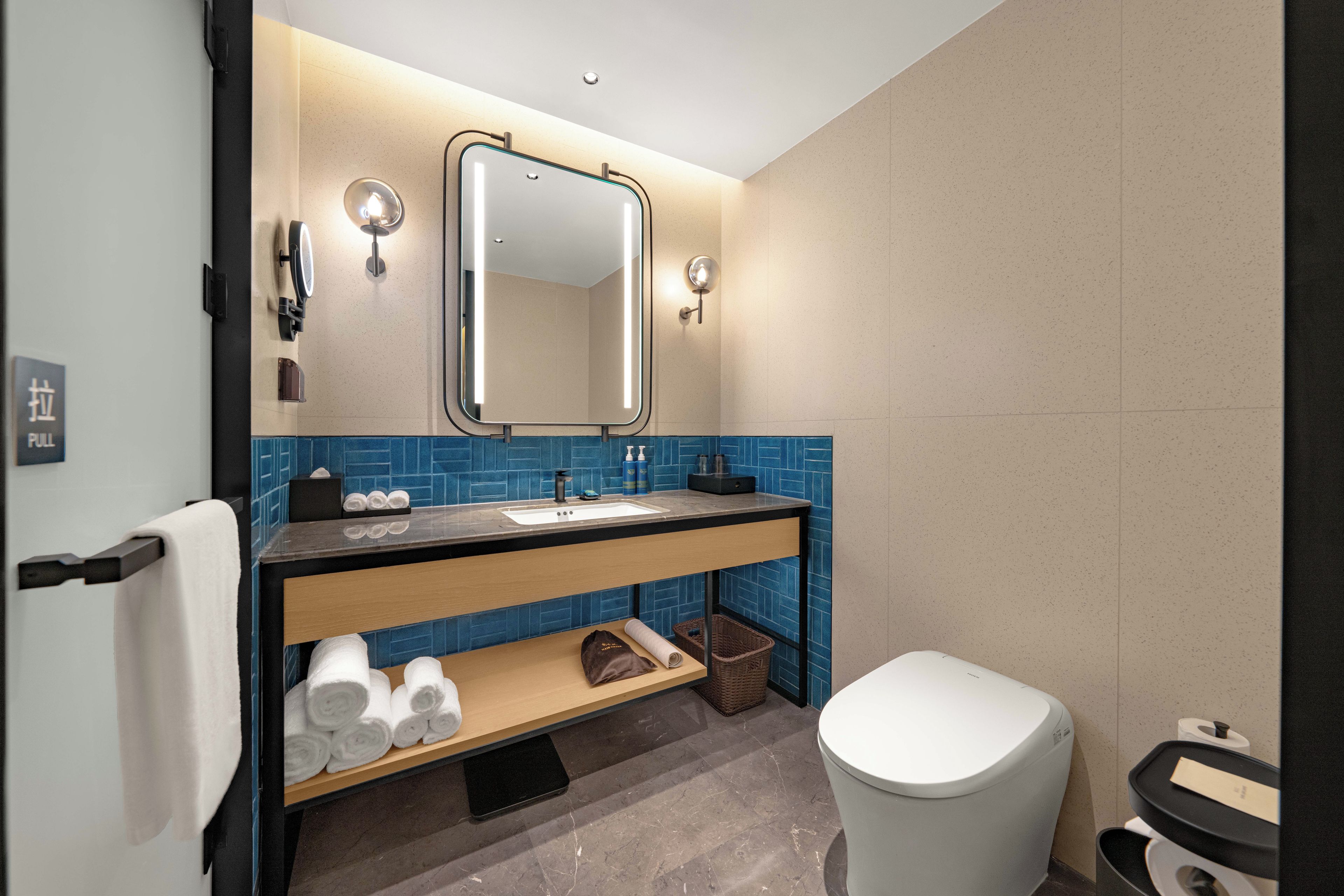 Un baño moderno con lavamanos, espejo, toallero y retrete.