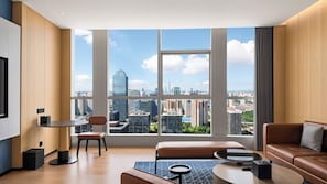 A modern living room with a large window, a sofa, a coffee table, and a chair.