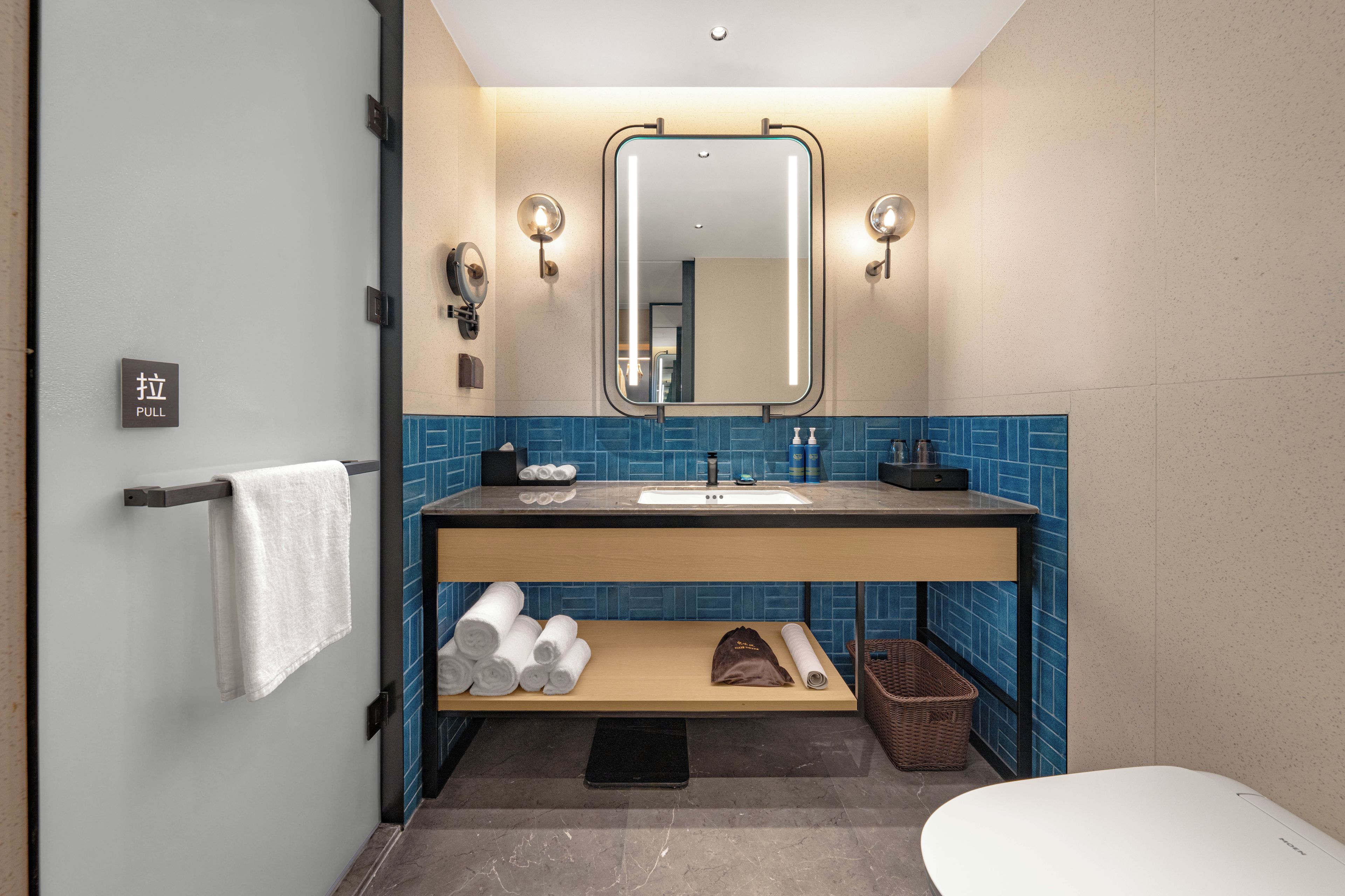 A modern bathroom with a towel rack, a mirror, a sink, and a toilet.