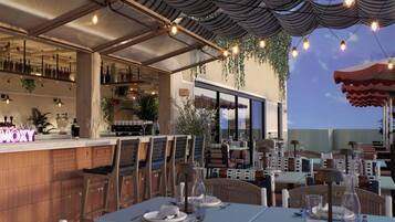 Un área de comedor al aire libre con mesas y sillas, un bar con botellas, y plantas colgantes.