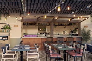 A restaurant interior with checkered flooring, tables with chairs, a bar area, and hanging lights. - Moxy St. Julian's Malta (St. Julian's)