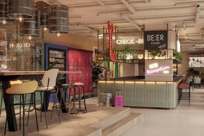A bar area with stools, a neon sign, and a reception desk. - Moxy St. Julian's Malta (St. Julian's)