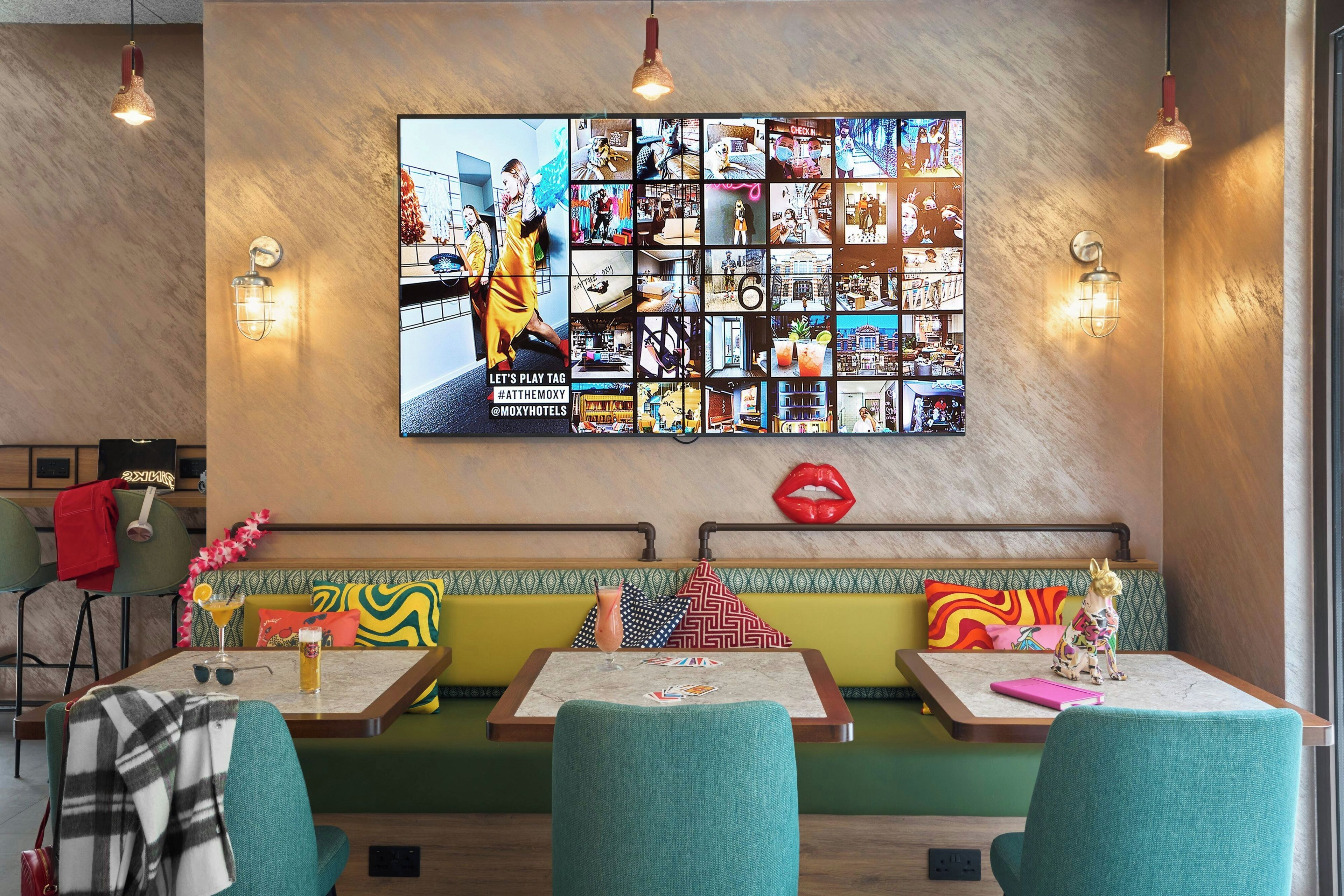 Interior de un restaurante con un collage de fotos en la pared, una zona de asientos con bancos y una barra.