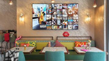 Interior de un restaurante con un collage de fotos en la pared, una zona de asientos con bancos y una barra.