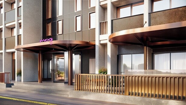 A modern hotel entrance with a curved canopy, large windows, and a visible outdoor area with plants. - Moxy St. Julian's Malta (St. Julian's)