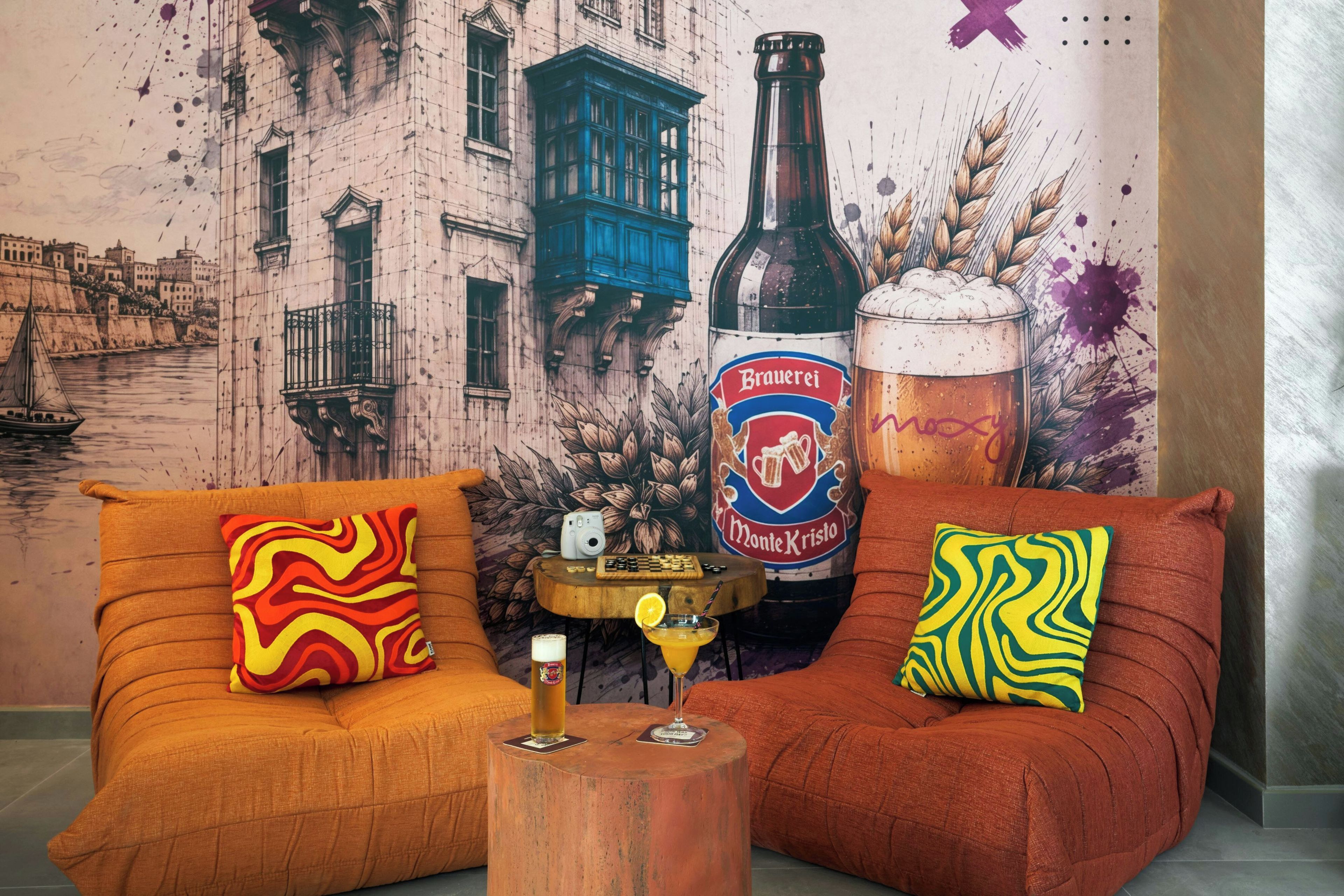 Habitación con dos sofás, una mesita de madera y un mural que muestra un paisaje urbano y una botella de cerveza.