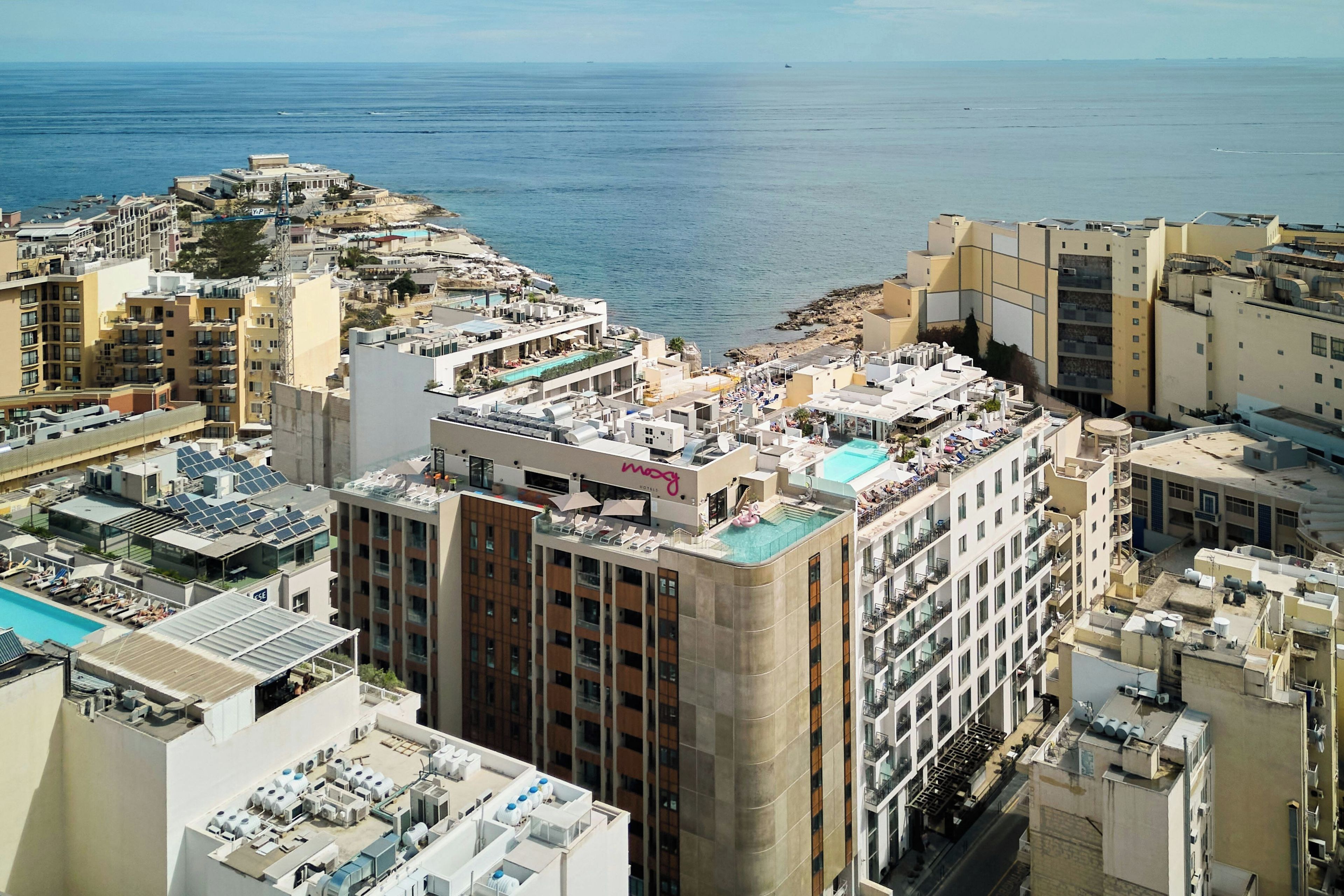 Un hôtel de grande hauteur doté de nombreux balcons, d’une piscine sur le toit et offrant une vue sur la mer.