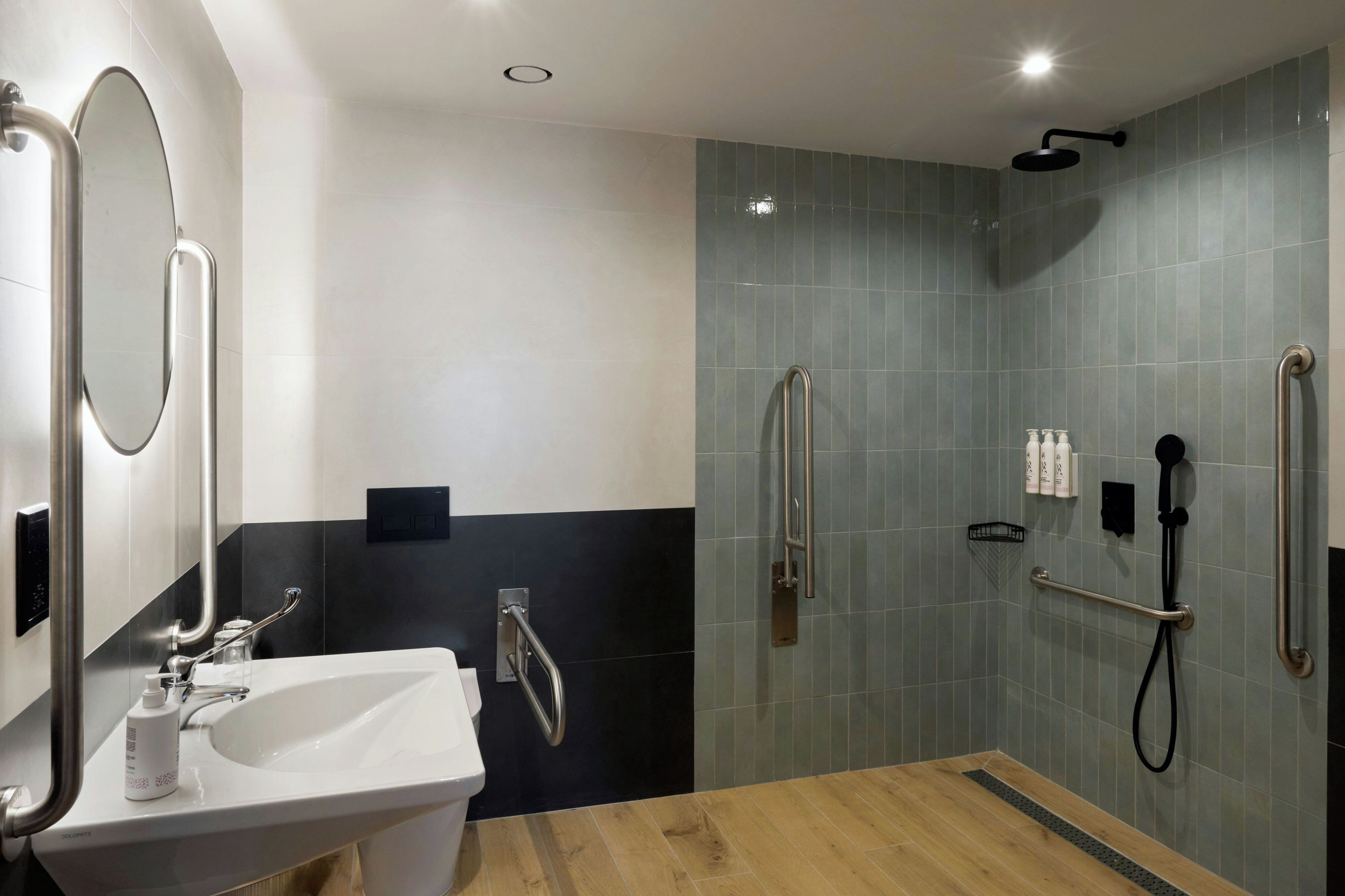 Un baño moderno con lavabo, espejo y zona de ducha.