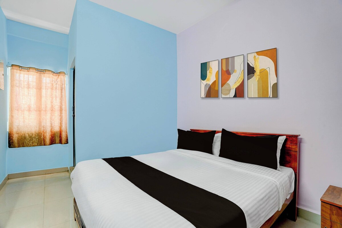 A hotel room with a bed, a nightstand, and a wall with three paintings.