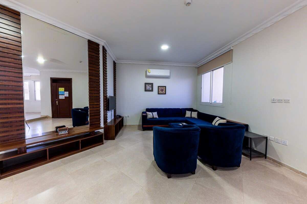 Una sala de estar con un sofá azul oscuro, un mueble de entretenimiento de madera y un espejo grande.