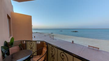 A balcony with a view of a beach and the sea.