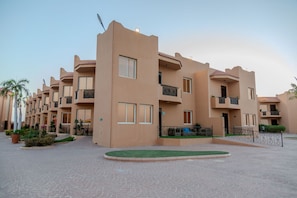 A multi-story hotel with balconies, a courtyard, and a paved walkway. - Alahlam Chalets For Holiday Homes (Yanbu)