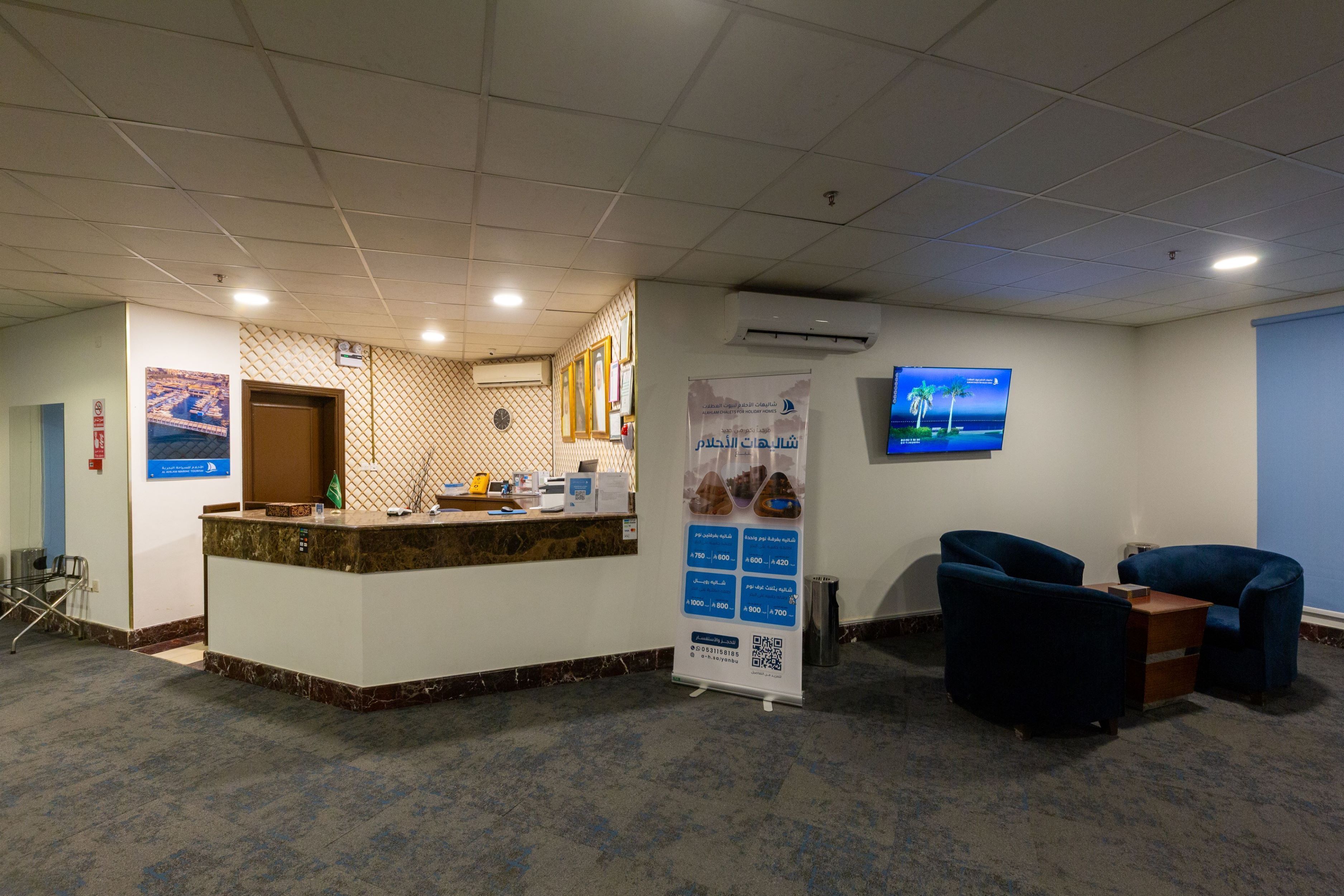 A reception area with a marble counter, a clock, and a digital screen displaying information.