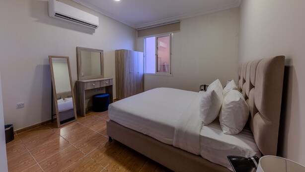 Une chambre à coucher comprenant un lit, une commode, un miroir, un appareil de climatisation et une fenêtre.