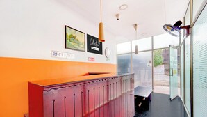 A reception area with a reception desk, a framed painting, a 'Collection' sign, and a 'Fire Exit' sign.