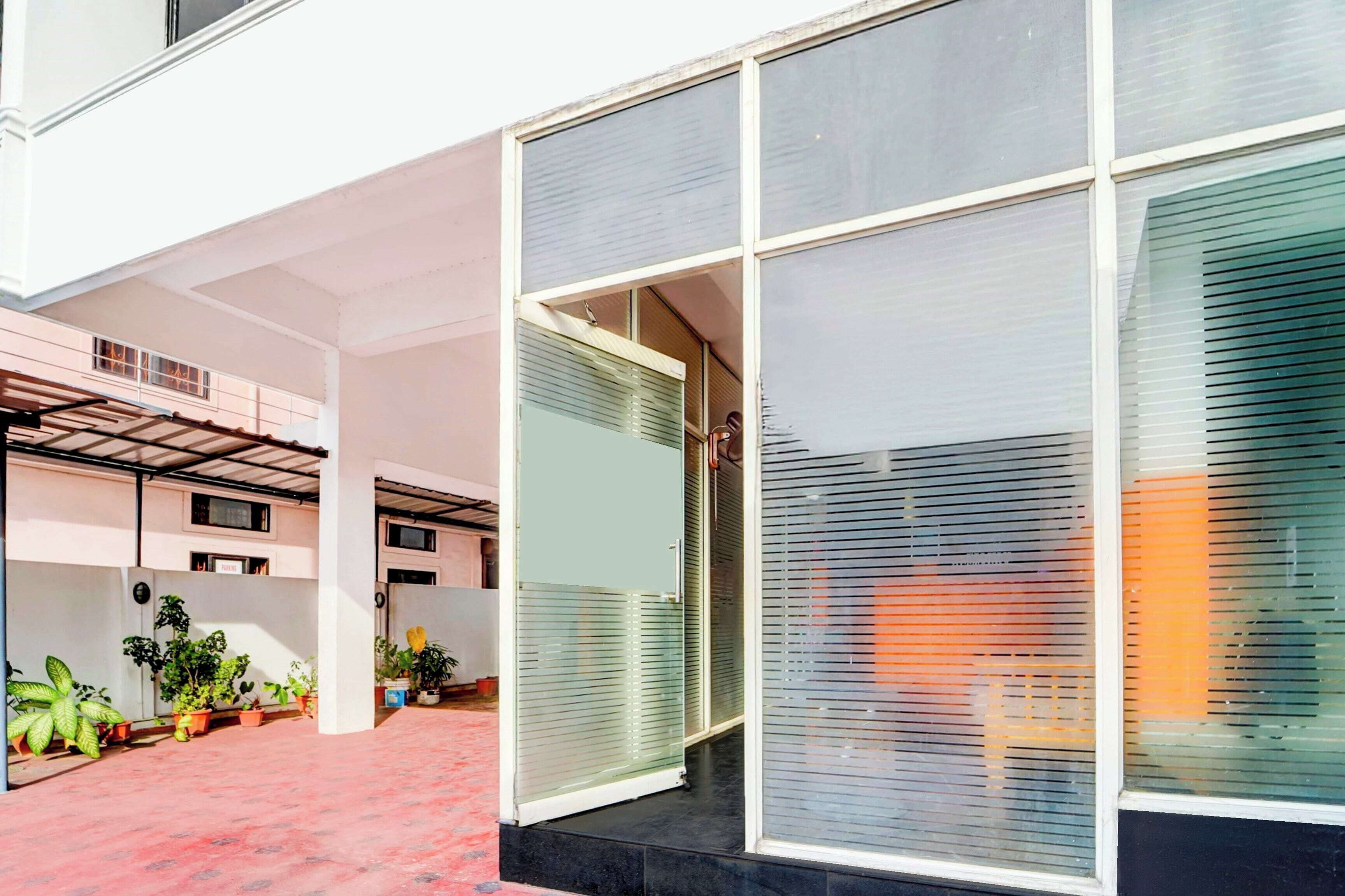 A modern building with large windows and a covered outdoor area with potted plants.