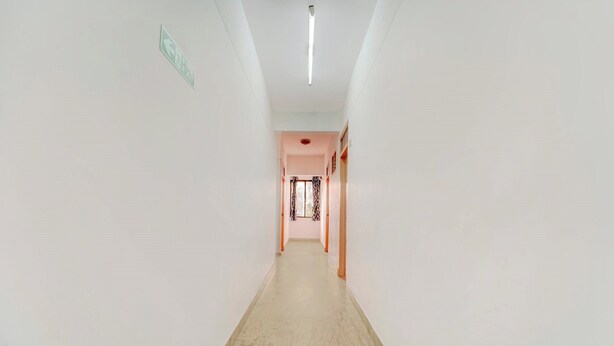 A corridor with a marble floor, white walls, and a fire exit sign.