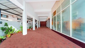 A corridor with a patterned floor, white walls, and potted plants.