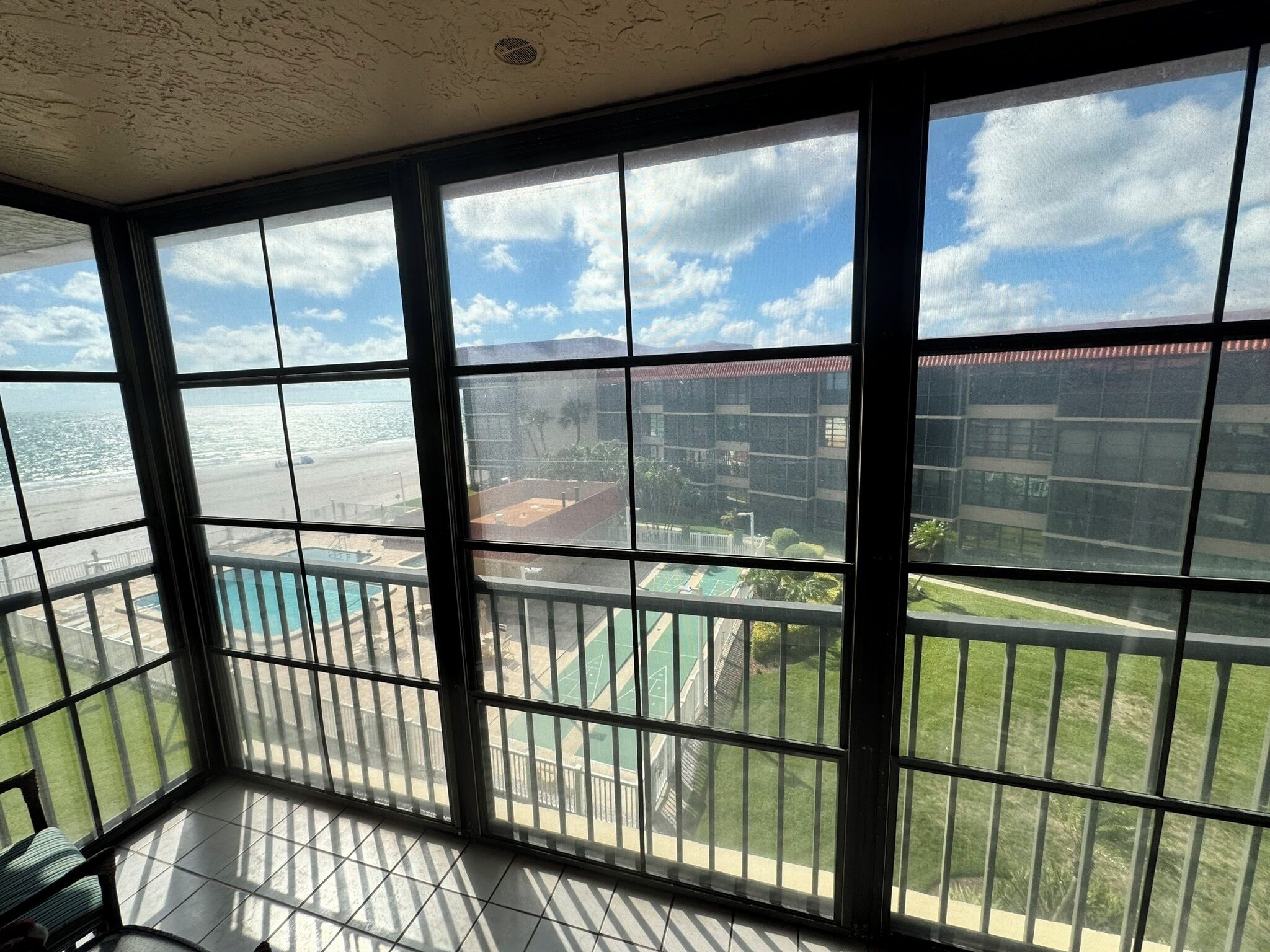 A balcony with a view of a beach and a pool.