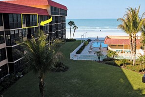 A hotel with a pool, a view of the beach, and palm trees. - Beachfront Condo (Redington Shores)