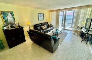 A living room with a sofa, a coffee table, a lamp, and a painting on the wall. - Beachfront Condo (Redington Shores)