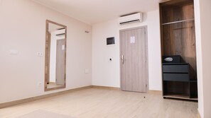 Una habitación con un armario de madera, un espejo y un escritorio pequeño con una computadora.