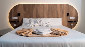 Un lit bien fait, avec du linge de lit blanc, une tête de lit en bois et deux interrupteurs fixés au mur.