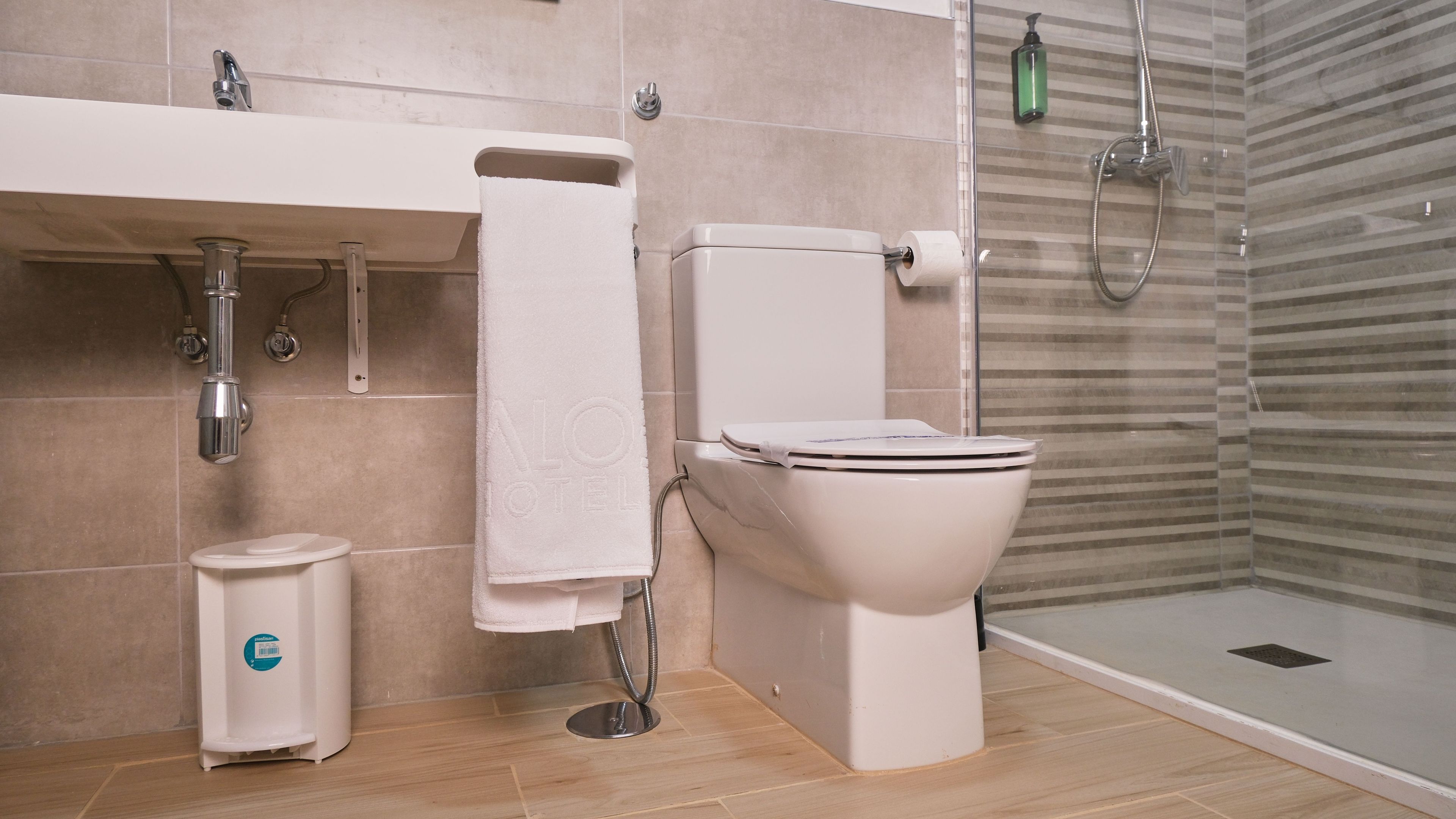 A modern bathroom with a toilet, a shower, and a sink.