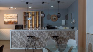 Una cocina moderna con una isla central, taburetes de bar, iluminación colgante y un adorno en la pared.