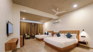 A hotel room with two beds, a TV, a ceiling fan, an air conditioning unit, and a small table with a phone.