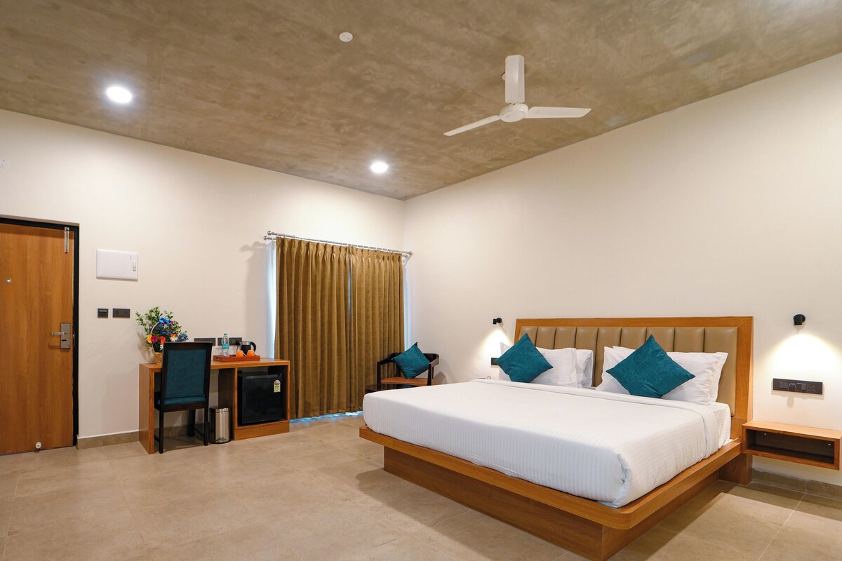 Una habitación de hotel con cama, escritorio, silla y ventilador de techo.