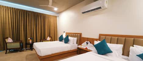 Habitación de hotel con dos camas, ventilador de techo, aire acondicionado y ventana con cortinas.