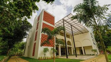 A modern building with a central courtyard, surrounded by lush greenery and palm trees.