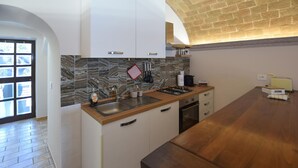 Eine Küche mit Marmorfliesenspiegel, Spüle, Herd und einer Holzausziehtafel.