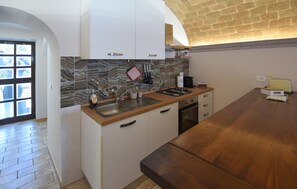 Eine Küche mit Marmorfliesenspiegel, Spüle, Herd und einer Holzausziehtafel.