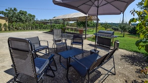 Eine Terrassengruppe im Freien mit Grill, Stühlen und Tisch unter einer Markise.