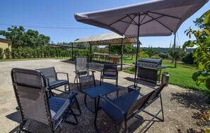 Eine Terrassengruppe im Freien mit Grill, Stühlen und Tisch unter einer Markise.