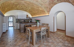 Eine geräumige Küche mit gewölbter Ziegeldecke, einem Essbereich mit Holztisch und -stühlen sowie Blick auf den angrenzenden Wohnbereich.