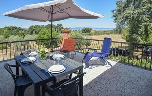 Eine Terrasse im Freien mit Esstisch, Stuhl und großem Sonnenschirm.