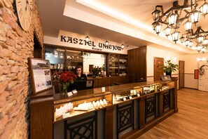 Un área de recepción con mostrador de madera, una mesa de recepción y un cartel que dice 'KASZEL UNIJOW'.