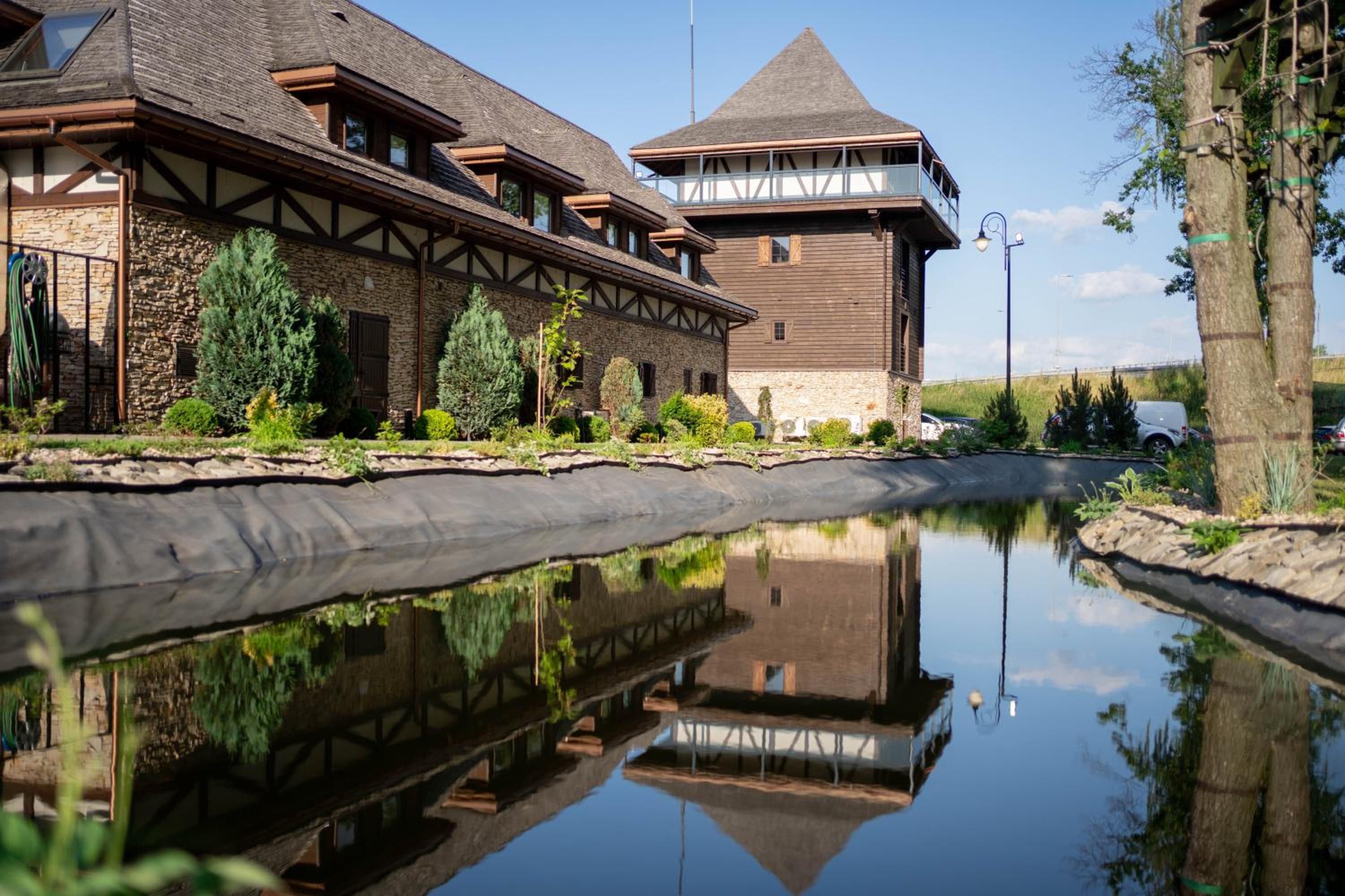 A building with a stone facade, a wooden deck, and a calm water body reflecting the structure.