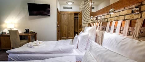 Une chambre d’hôtel avec deux lits, un téléviseur fixé au mur, une tête de lit en bois et une petite table avec une lampe.