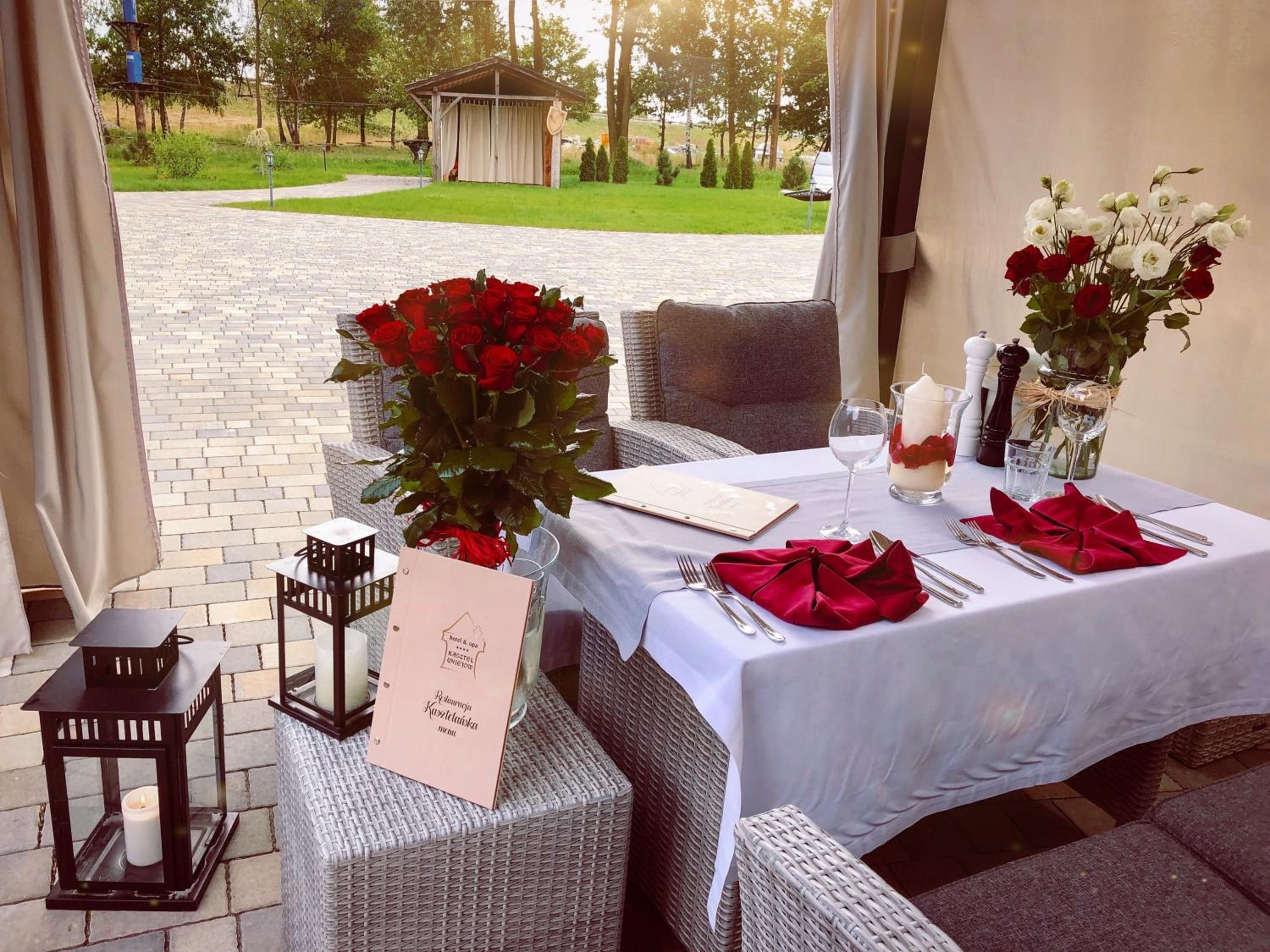 An outdoor dining area with wicker furniture, a table set with red napkins, and a sign indicating a restaurant.