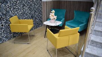Un intérieur moderne avec deux chaises jaunes, une chaise turquoise et une table en marbre agrémentée d’un vase de fleurs.